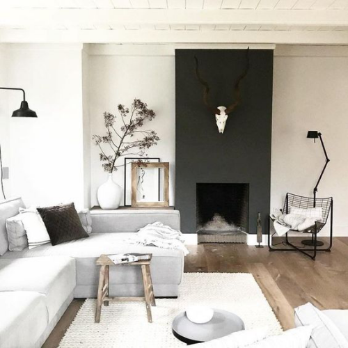 Wohnzimmer in Schwarz-Weiß Holzboden weitere Holzelemente Stuhl Bilderrahmen
