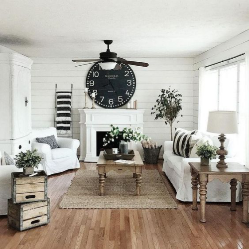 Wohnzimmer in Schwarz-Weiß Vintage Holzkisten zwei Holztische große schwarze Wanduhr viele Blumen