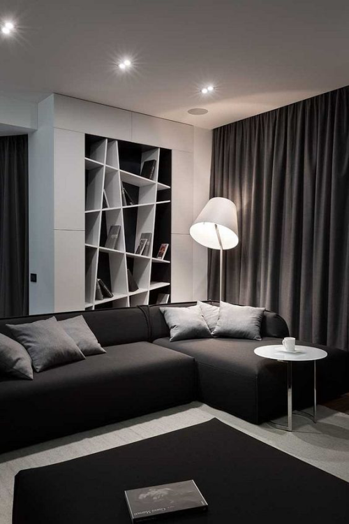 Wohnzimmer in Schwarz-Weiß Zwischentöne Graunuancen dunkles Interieur Lampe Regal Vorhänge Beistelltisch