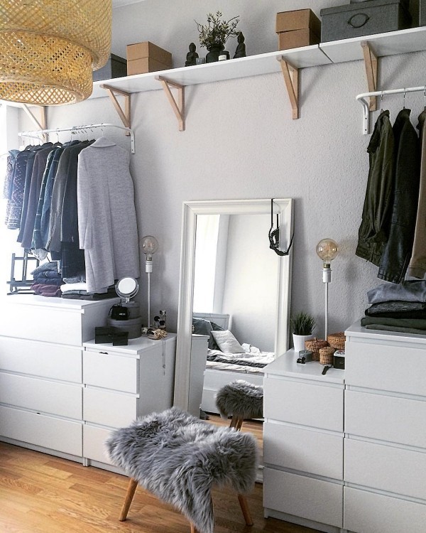 Jeanskleidung im offenen Kleiderschrank und ein großer Spiegel an die Wand gelehnt 