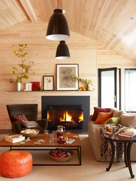 Herbstdeko im Wohnzimmer Holzdecke brennendes Feuer im Kamin warme Farben ringsum sehr gemütlich wohlig