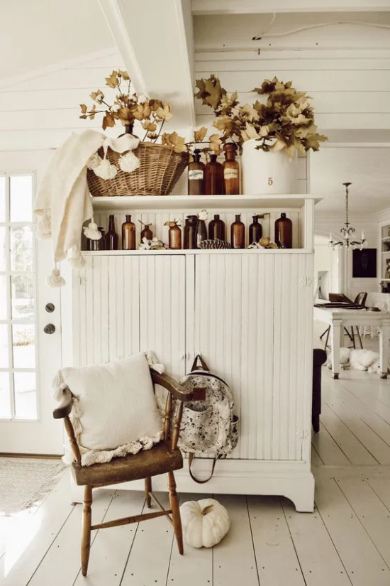 Herbstdeko im Wohnzimmer Schrank in Vintage Style herbstlich dekorieren Gläser Vase Flechtkorb mit bunten Zweigen