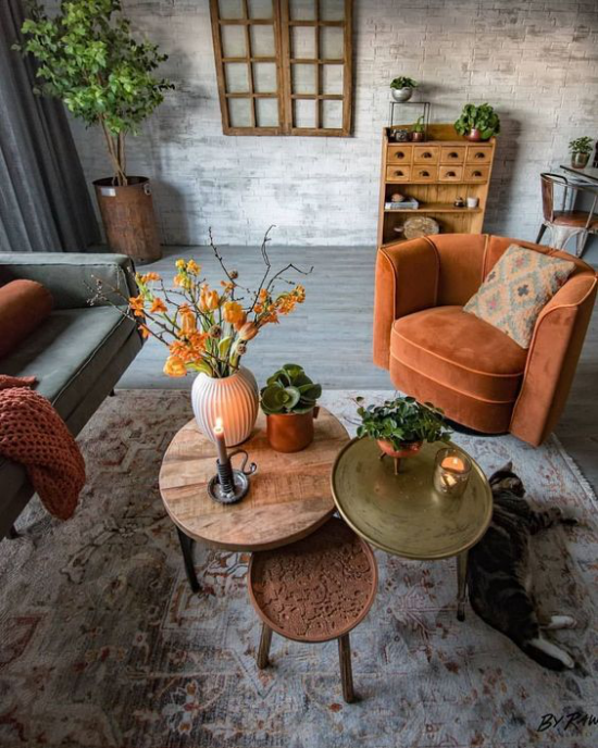 Herbstdeko im Wohnzimmer orangenfarbener Sessel drei kleine runde Tische dekoriert sehr gemütliche Atmosphäre