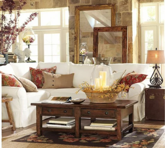 Herbstdeko im Wohnzimmer weißes Ecksofa Holztisch dekoriert bunte Kissen Kerzen Zweige in Vase gemütlich und wohlig