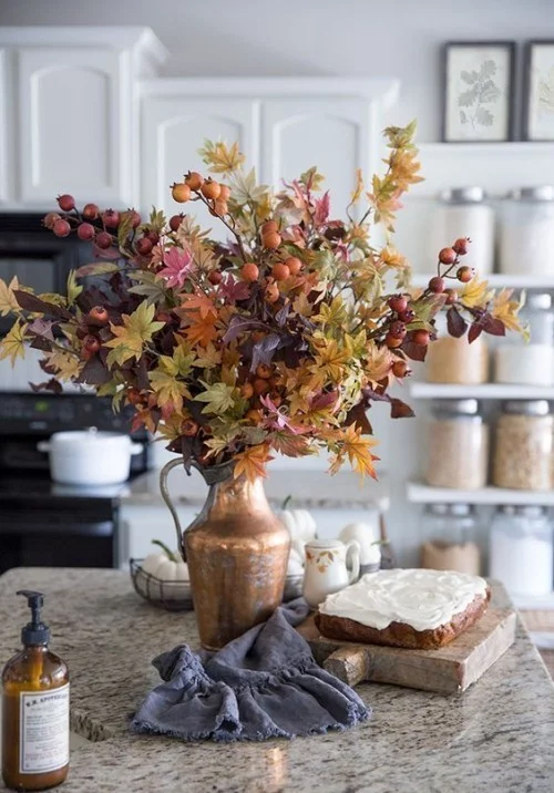 Herbstdeko in der Küche Metallgefäß buntes Herbstlaub rote Beeren schmücken die Kücheninsel