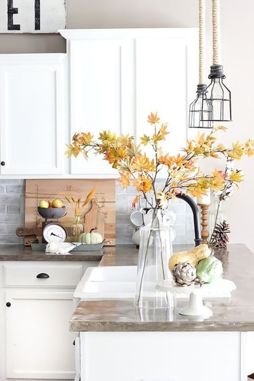 Herbstdeko in der Küche Vase aus Glas mit Zweigen bunte Herbstblätter kleine Kürbisse Tannenzapfen