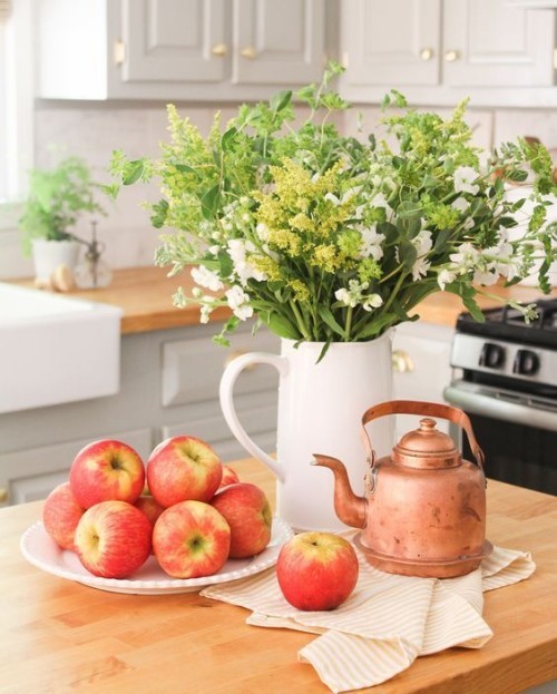 Herbstdeko in der Küche reife Äpfel weiße Porzellankanne mit Herbstblumen