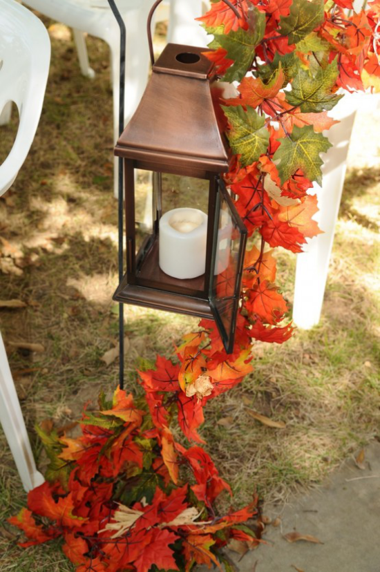 Laternen tolle Herbstdeko mit Laternen weiße Kerze stilvolle Laterne draußen im Freien bunte Herbstblätter als Girlande