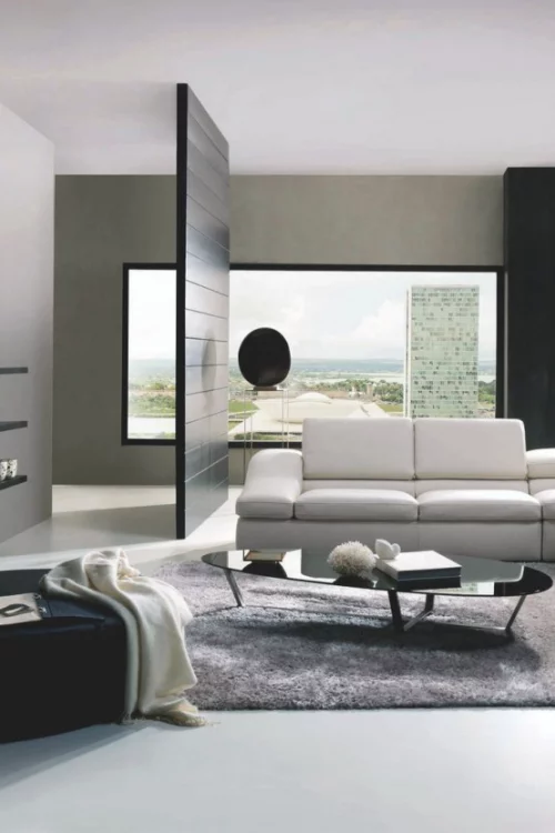 Minimalismus im Wohnzimmer eleganter Raumteiler trennt den stilvollen Raum ab Sofa Teppich kleiner Tisch Wurfdecke Sessel