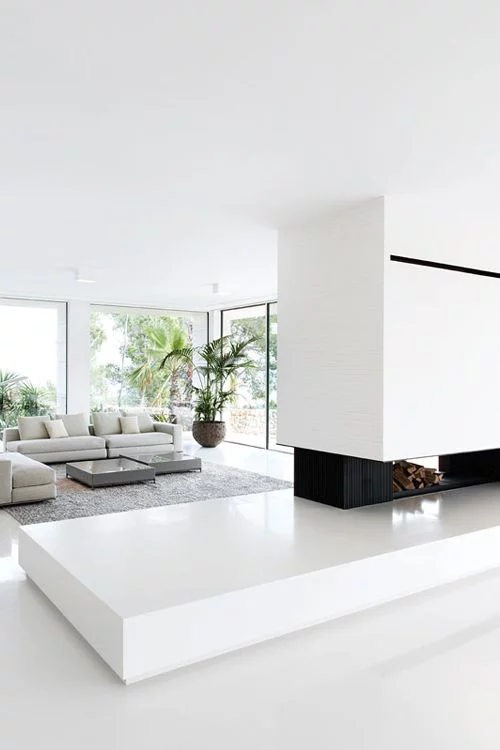 Minimalismus im Wohnzimmer perfektes Raumdesign viel Weiß Kamin grüne Pflanze in der Ecke