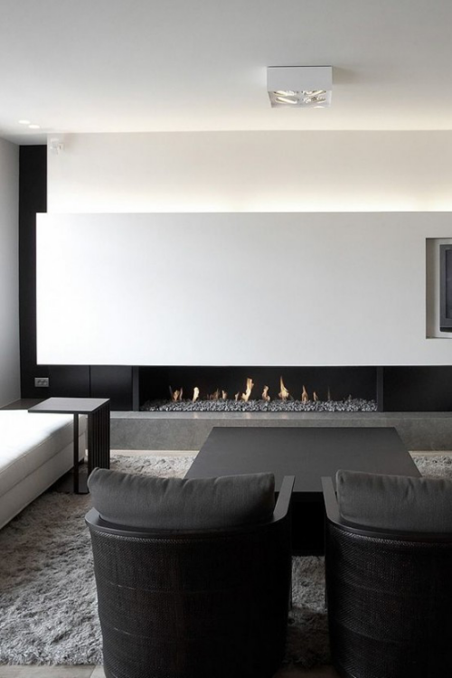 Minimalismus im Wohnzimmer perfektes Raumdesign weiß grau zwei schwarze Sessel im Vordergrund Kamin im Hintergrund