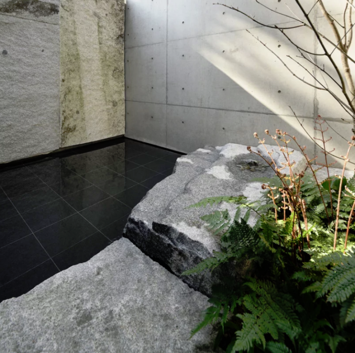 Minimalistisches Haus aus Stein und Beton in Japan Innenhof glatte mattschwarze Fliesen Naturstein große Platten Baum grünes Farn