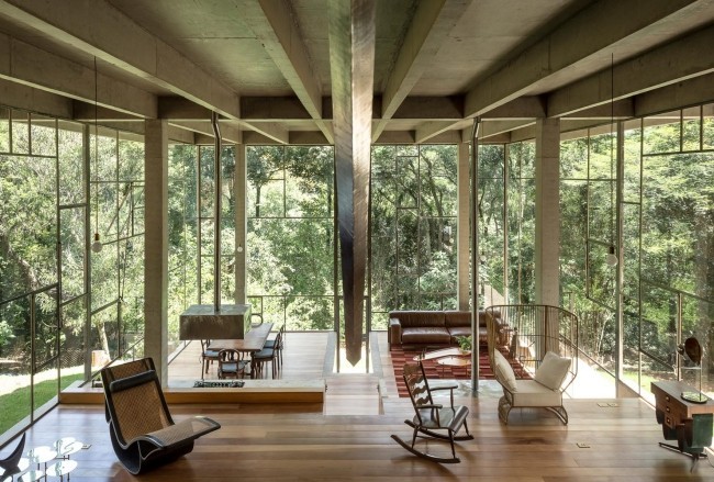Modernes Haus aus Glas und Beton im Regenwald errichtet geräumiges Wohnzimmer hohe Glaswände Blick ins Freie