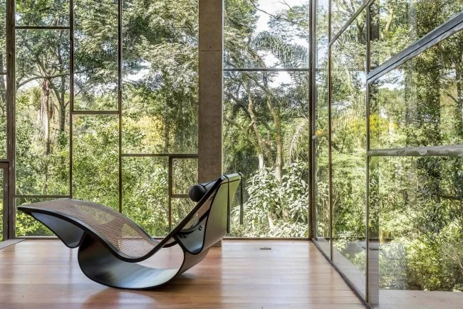 Modernes Haus aus Glas und Beton im Regenwald errichtet schicker Schaukelsessel ein Mix aus modernem und Retro Design