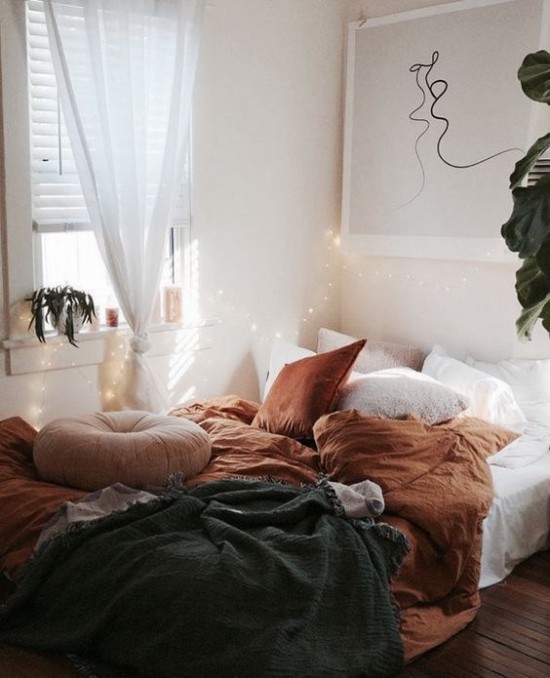 Schlafzimmer herbstlich gestalten Bettbezug in warmen Herbstfarben Brauntöne und Türkis Sonnenlicht und Lichterkette