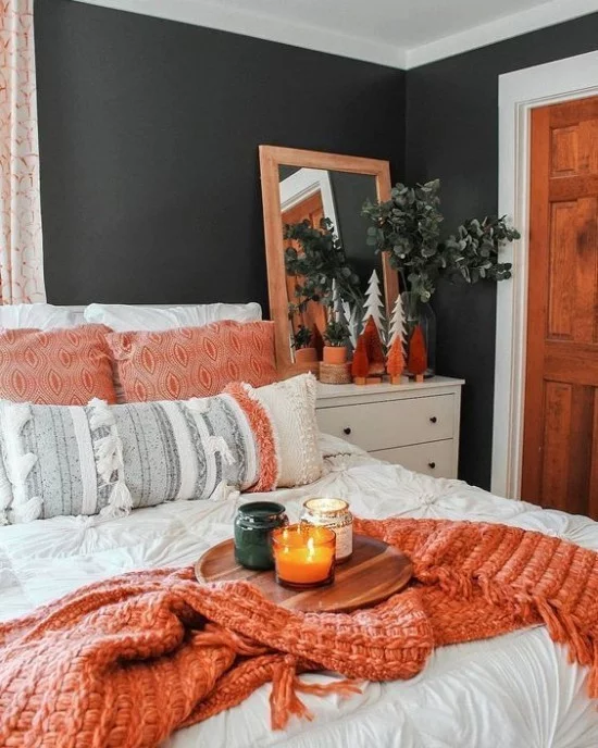 Schlafzimmer herbstlich gestalten Kontrast dunkle Wand in Schwarzgrün Bettwäsche in Weiß Wurfdecke in Lachsfarbe Holz Kissen Zimmerpflanze