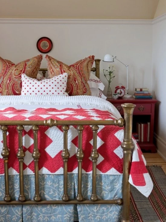 Schlafzimmer herbstlich gestalten rustikales Ambiente Bettzeug in Rot und Weiß gemusterte Kissen Nachtisch Lampe Bücher