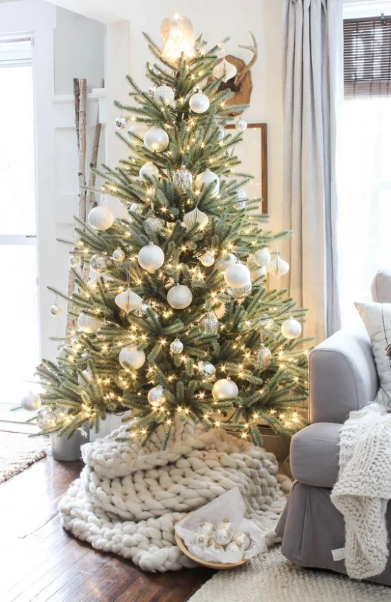 Weihnachtsbaum schmücken mit weißen Christbaumkugeln und vielen kleinen Lichtern