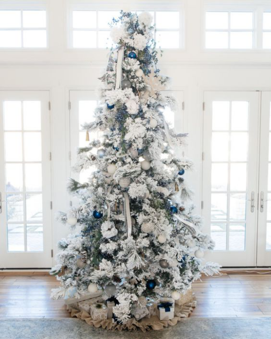 Weihnachtsbaum schmücken in Weiß und Silber vor dem Fenster platziert ein paar glänzende blaue Kugeln als Akzente