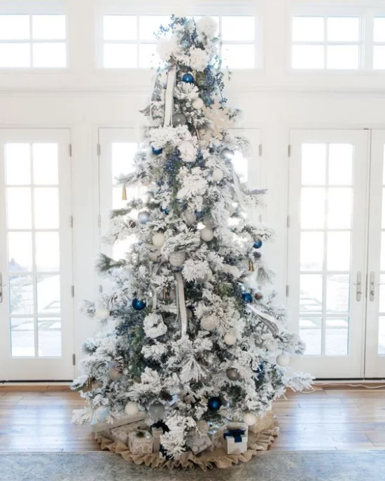 Weihnachtsbaum steht vor dem Fenster und ist mit glänzenden blauen Kugeln dekoriert