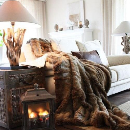 Winterdeko im Wohnzimmer gemütliche Atmosphäre viel Wärme Sofa mit heller Polsterung schokobraune warme Decke Laterne mit Kerzen Lampen