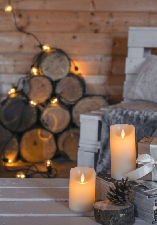 Hygge Feeling zu Weihnachten angezündete Kerzen Lichterkette Brennholz im Hintergrund