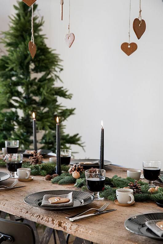 Hygge Feeling zu Weihnachten festlich gedeckte Tafel aus Holz Kerzen Tannenzweige Tannenbaum nebenan