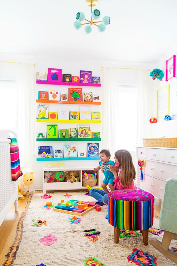 Kunterbuntes Babyzimmer weicher Teppich Regal bunte Bücher Spielsachen bunter Hocker