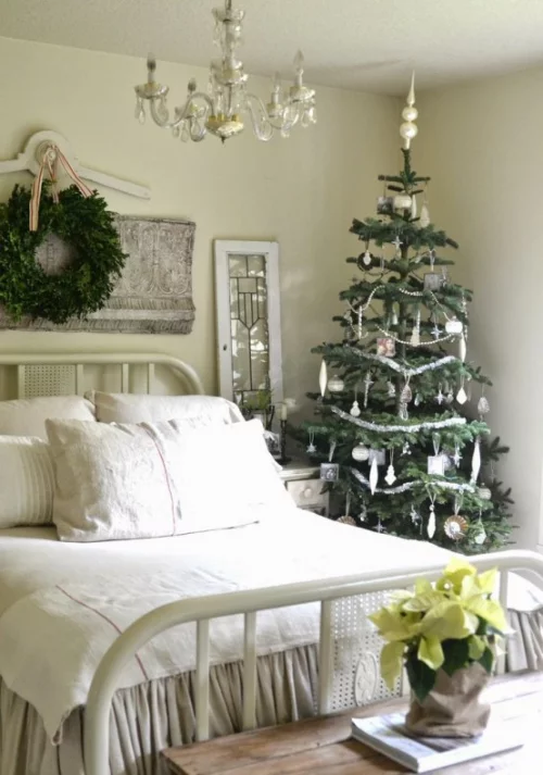 Gemütliches Schlafzimmer im Winter gestalten großer Schlafbett weiß-cremige Bettwäsche kleiner Christbaum daneben Weihnachtsstern Kranz
