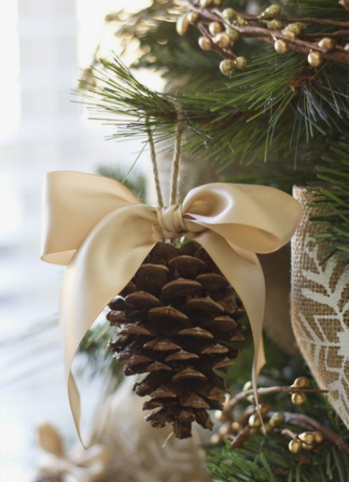 Rustikale Weihnachtsdeko selber machen Tannenzapfen mit einer cremefarbenen Schleife für den Christbaum