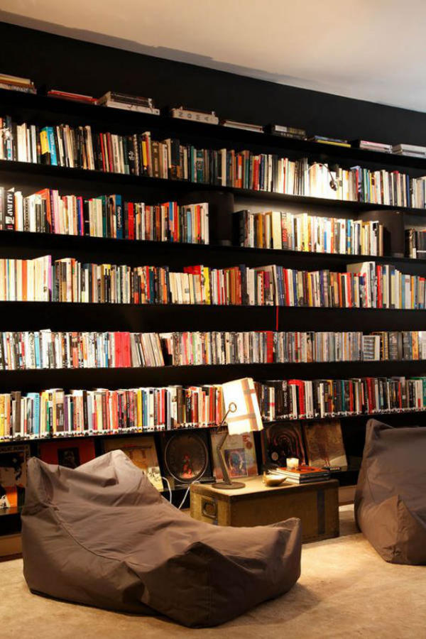 Moderne Hausbibliothek Bücherwand zahlreiche Bücher bequeme Sitzpuffs