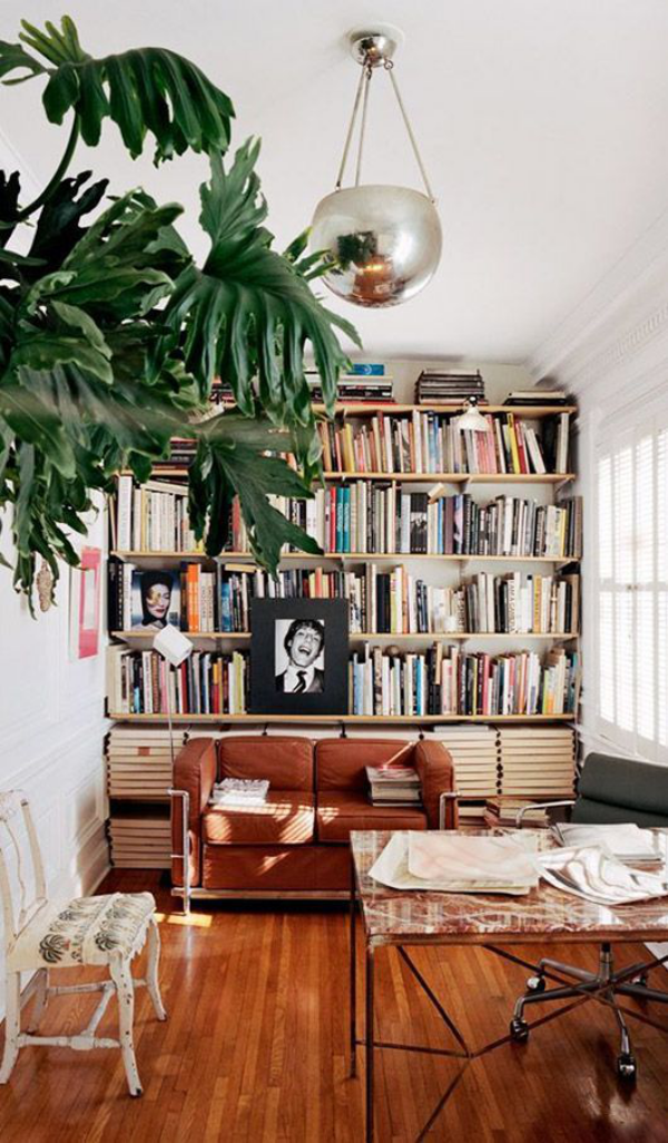 Moderne Hausbibliothek Sofa Tisch auf Rädern viel Holz warme Farben grüne Zimmerpflanze