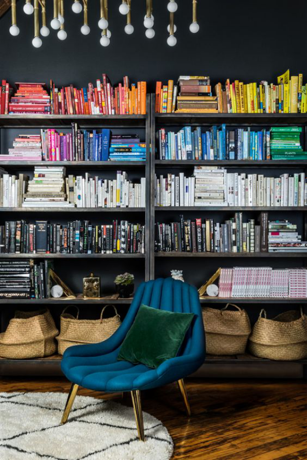 Moderne Hausbibliothek blauer Sessel Bücherwand Bücher anordnen nach Farben