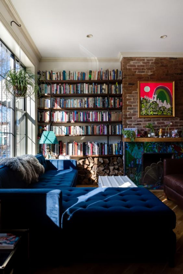 Moderne Hausbibliothek eine Wand mit Büchern neben Kamin komfortable Couch in Marineblau Licht