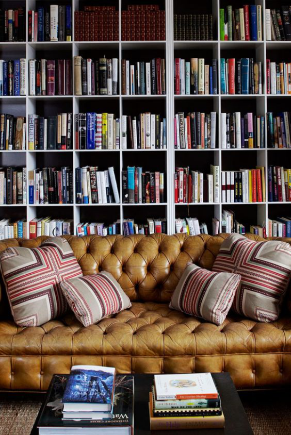 Moderne Hausbibliothek schickes Ledersofa einige weiche Kissen viele Bücher gemütlich