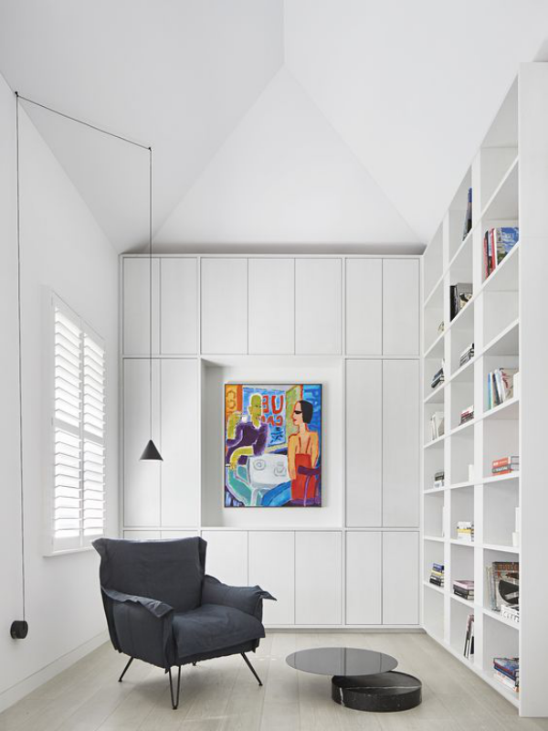 Moderne Hausbibliothek weißes Raumdesign  buntes Wandbild als Akzent schwarzer Sessel