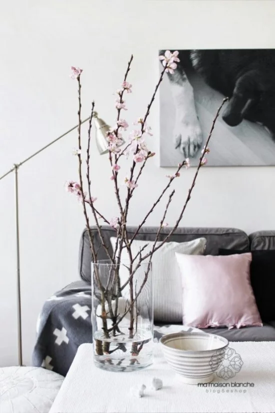 Frühlingsdeko mit Kirschblüten ein paar Kirschzweige im Glas im Wohnzimmer auf dem Kaffeetisch