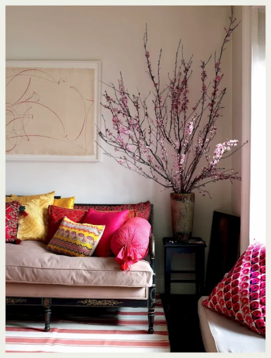 Frühlingsdeko mit Kirschblüten große Vase schön arrangierten Kirschzweige in der Ecke des Wohnzimmers Sofa bunte Wurfkissen