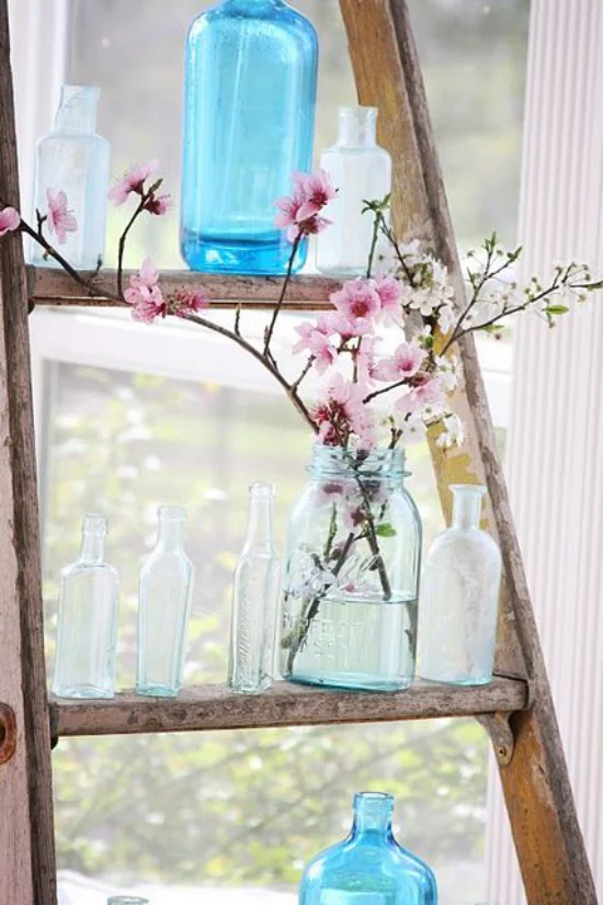 Frühlingsdeko mit Kirschblüten zwei drei Zweige rosa Blüten im Glas auf der alten Holzleiter