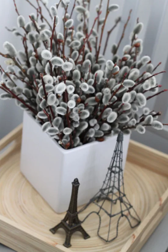 Frühlingsdeko mit Weidenkätzchen in der Vase arrangiert Eifelturm Souvenirs daneben