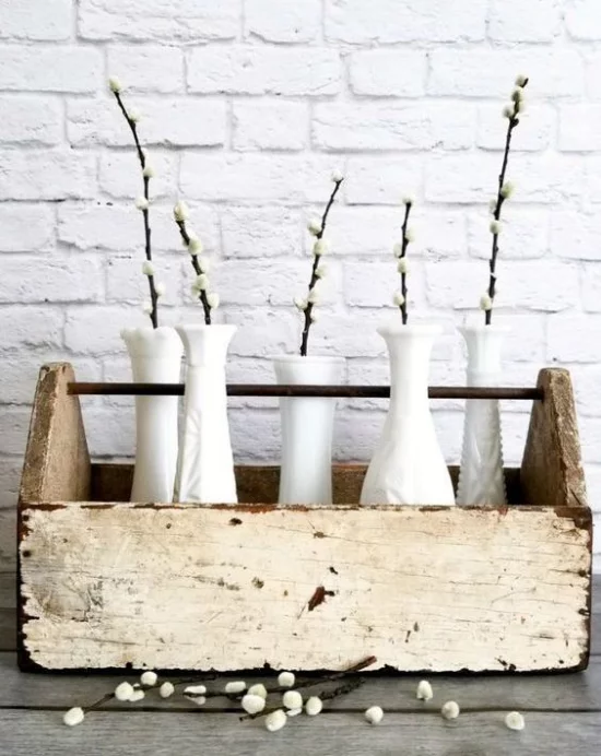 Frühlingsdeko mit Weidenkätzchen in kleinen weißen Vasen im Vintage Kasten
