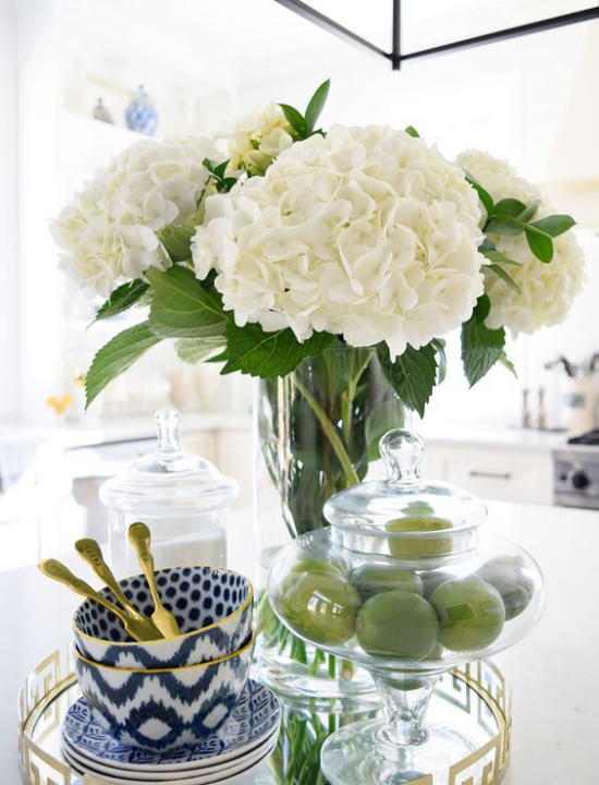 Küche frühlingshaft dekorieren weiße Hortensien in Vase aus Glas grüne Zitronen elegantes Kaffeeservice