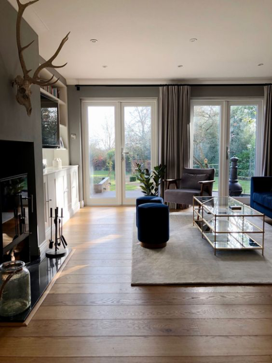 Wohnzimmer optisch erweitern einladender und gemütlicher Raum Tageslicht hohe Fenster Beige dominiert dunkelblaue Akzente