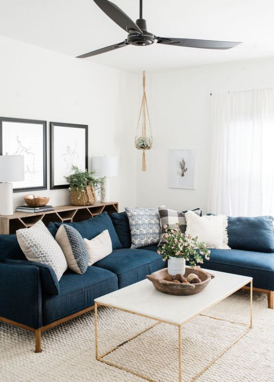 Wohnzimmer optisch erweitern weiß und dunkelblau im Kontrast viel Tageslicht keine Grenzen dunkles Sofa als Akzent
