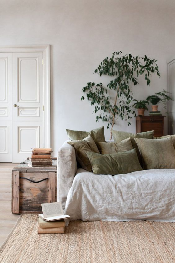 Zeitgemäße Raumgestaltung helle Farben Sofa Teppich olivgrüne Deko Kissen eine Grünpflanze