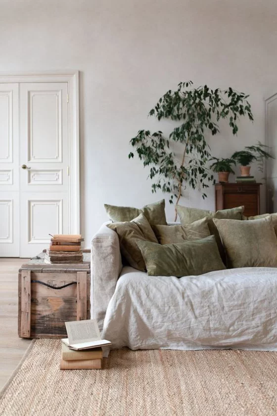 Zeitgemäße Raumgestaltung helle Farben Sofa Teppich olivgrüne Deko Kissen eine Grünpflanze