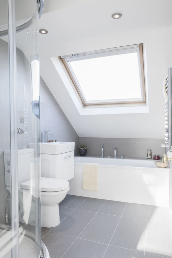 Zeitgemäße Raumgestaltung helles Badezimmer ganz in Weiß Badewanne unter der Dachschräge Duschecke hinter Glaswand