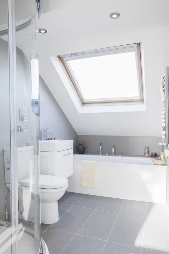 Zeitgemäße Raumgestaltung helles Badezimmer ganz in Weiß Badewanne unter der Dachschräge Duschecke hinter Glaswand