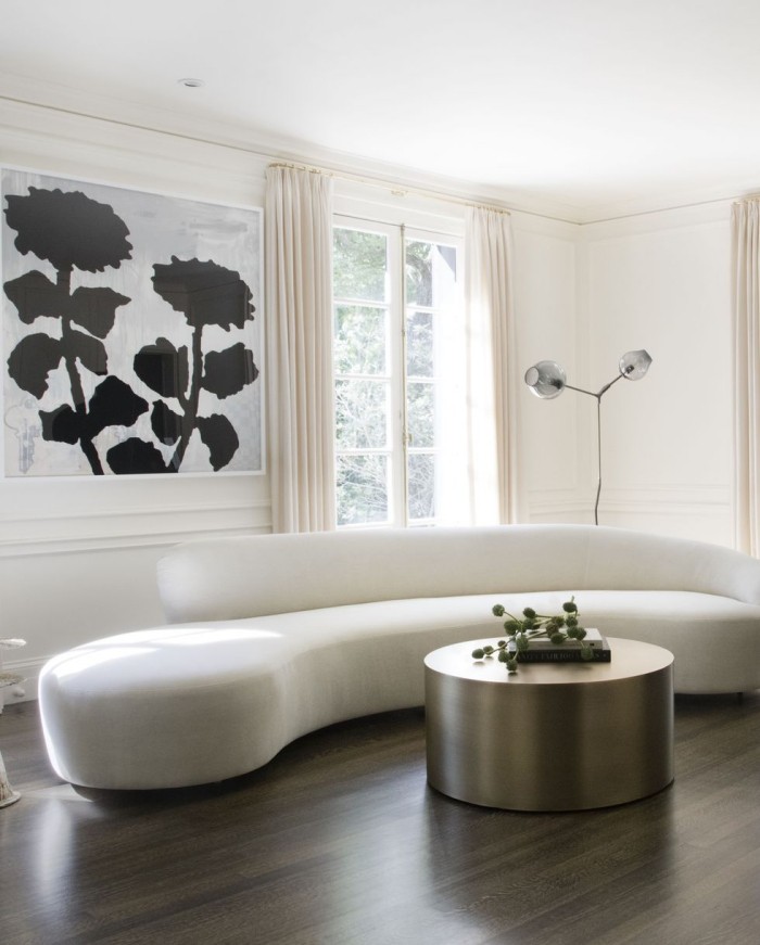 Geheimnisse des Innendesigns enthüllt elegant eingerichtetes Wohnzimmer runde weiße Couch runder Kaffeetisch im Metallglanz dunkler Boden als Kontrast