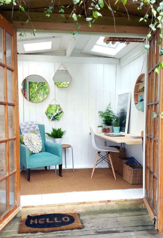 Outdoor - Trends 2020 Gartenhaus als praktisches Heimbüro eingerichtet Tisch Stuhl blauer Sessel Wandspiegel